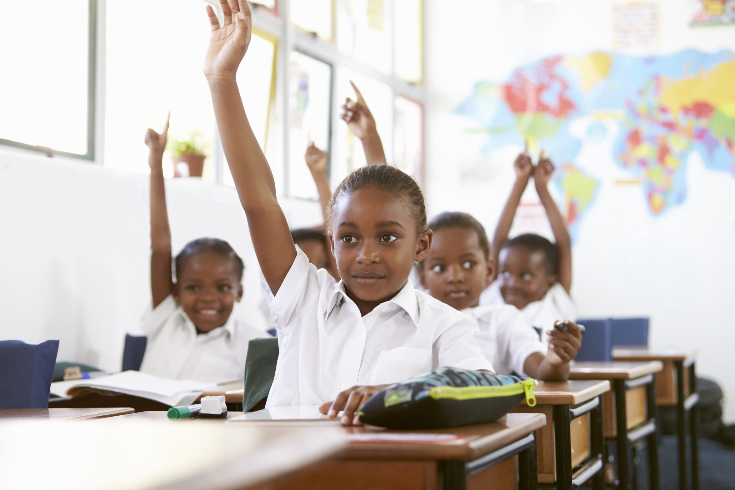 Students raising hands in class learning